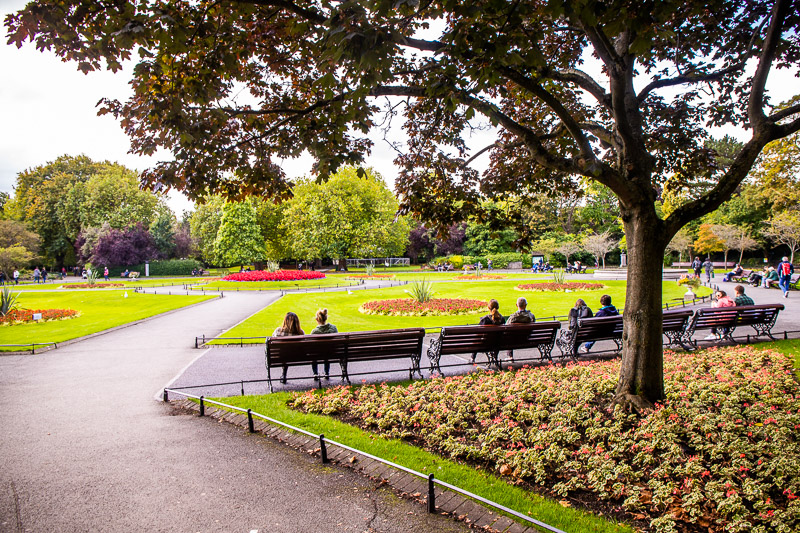 People sitting on park benches overlooking gardens