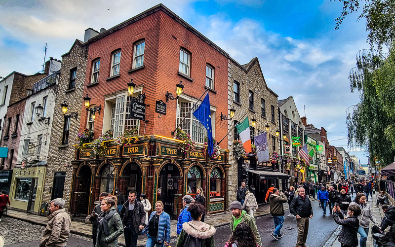 People walking along a street outside a pub in Dublin
