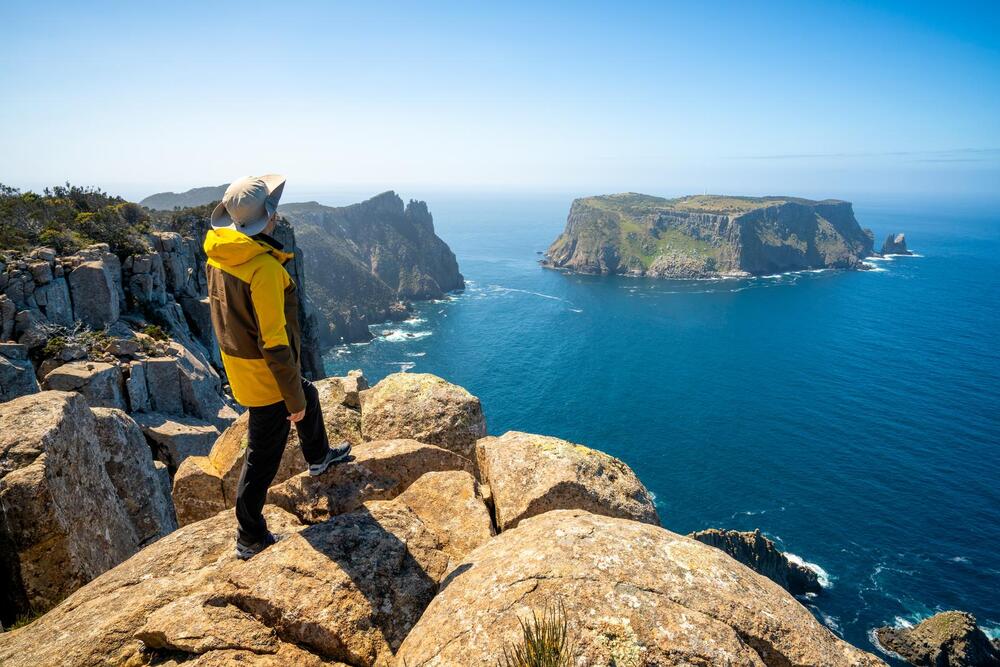 young man trekker hiking on beautiful coast cliff of Tasman National Park in Tasman peninsula