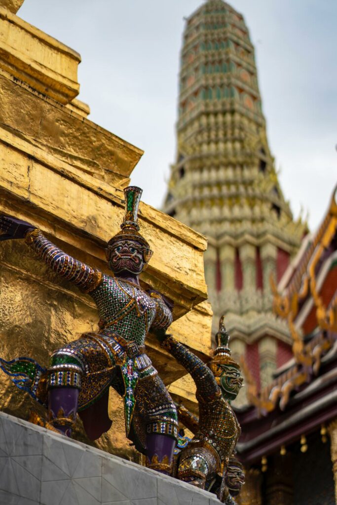 small figurine decoratons holding up golden temple of the Grand Palace
