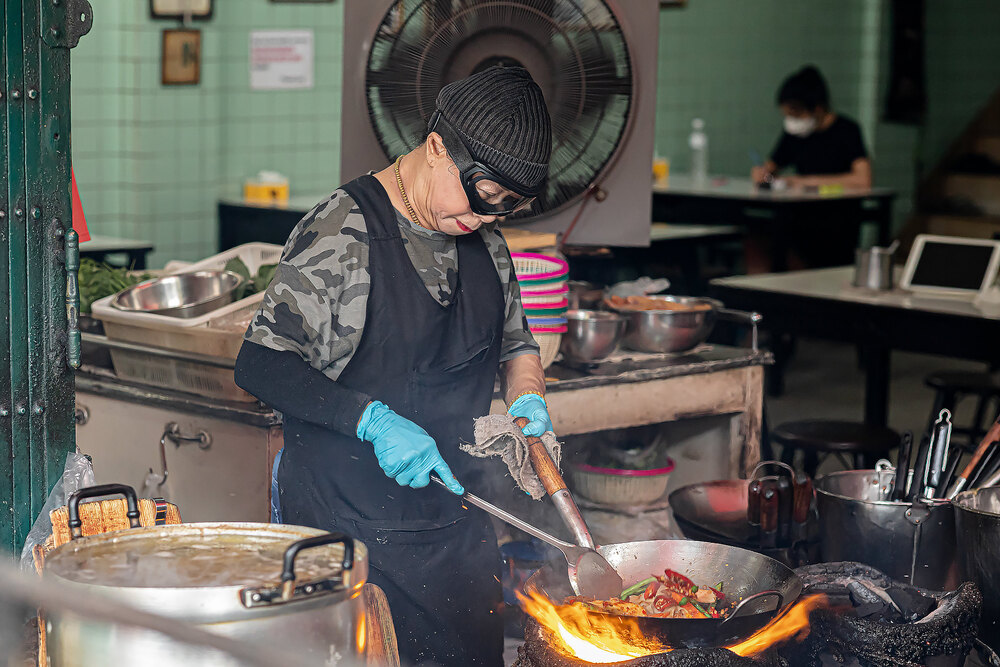 woman cooking over a wok