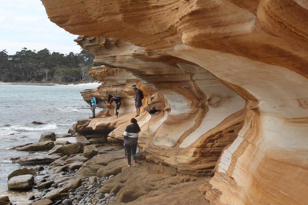 people climbing painted cliffs