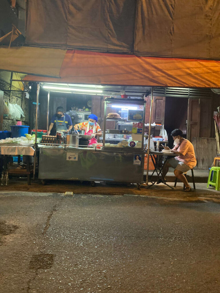 person cooking food on thai street cart