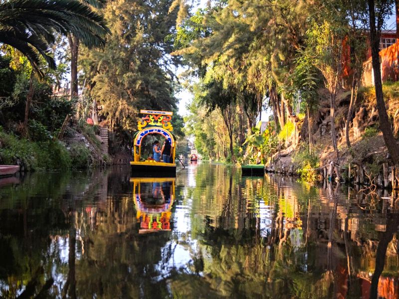 Boat floting down a lake surrounded by gardens in Mexico City