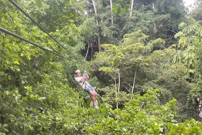 man zip lining through the jungle in jamaica