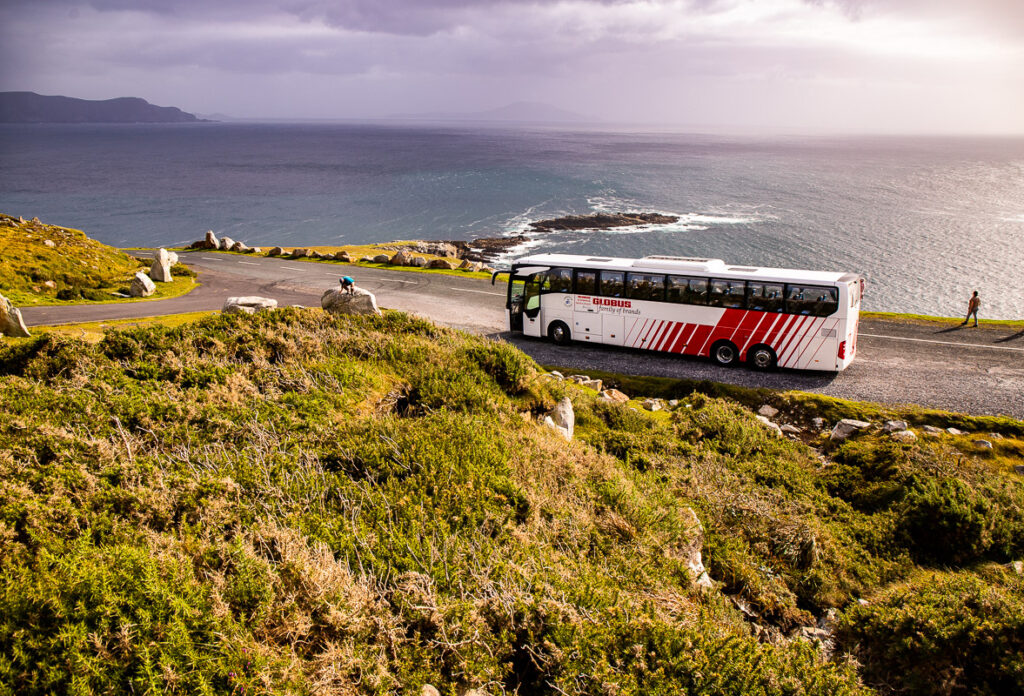 big tour bus driving along a coastal road in Ireland