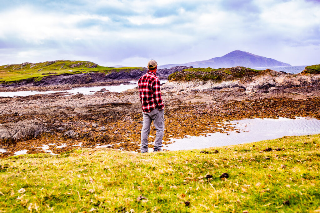 Man standing on a rugged coastline overlooking rocks