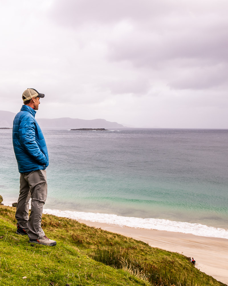 Man standing on a cliff overlooking a beach