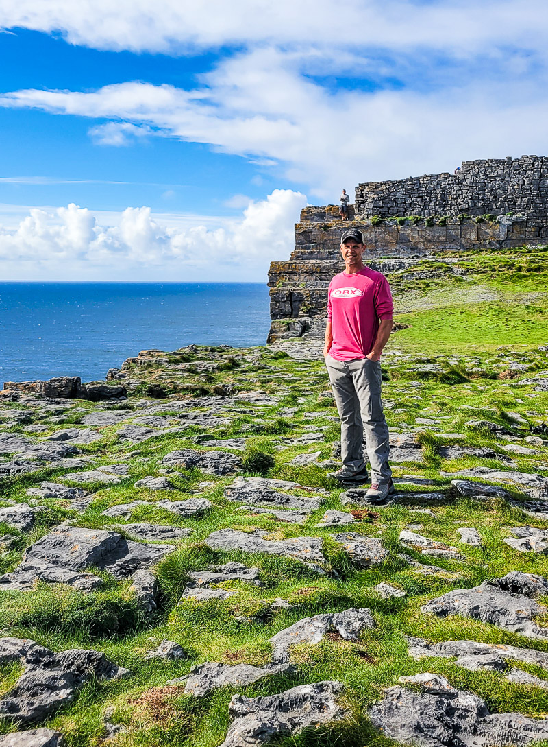 man standing near irish cliffs
