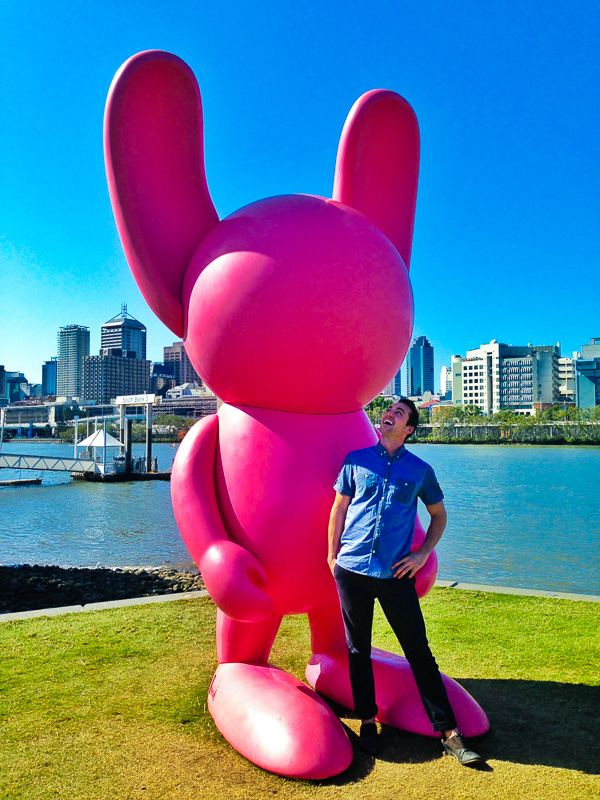man standing next to giant pink inflatable bunny
