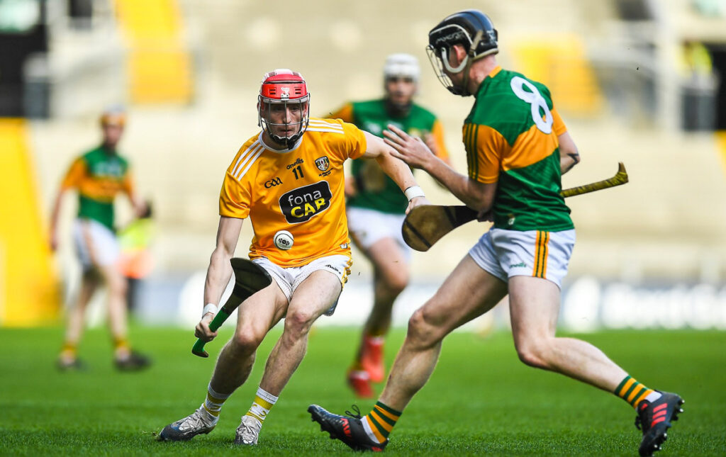 Two men playing the game of hurling with sticks and a ball
