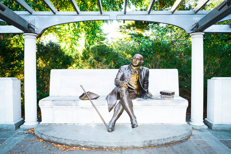 stone statue of george mason istting on bench