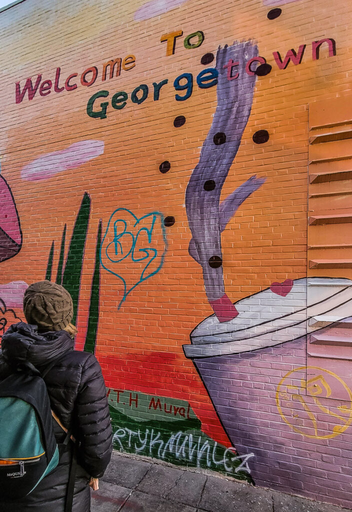 Woman looking at a street mural that says welcome to Georgetown