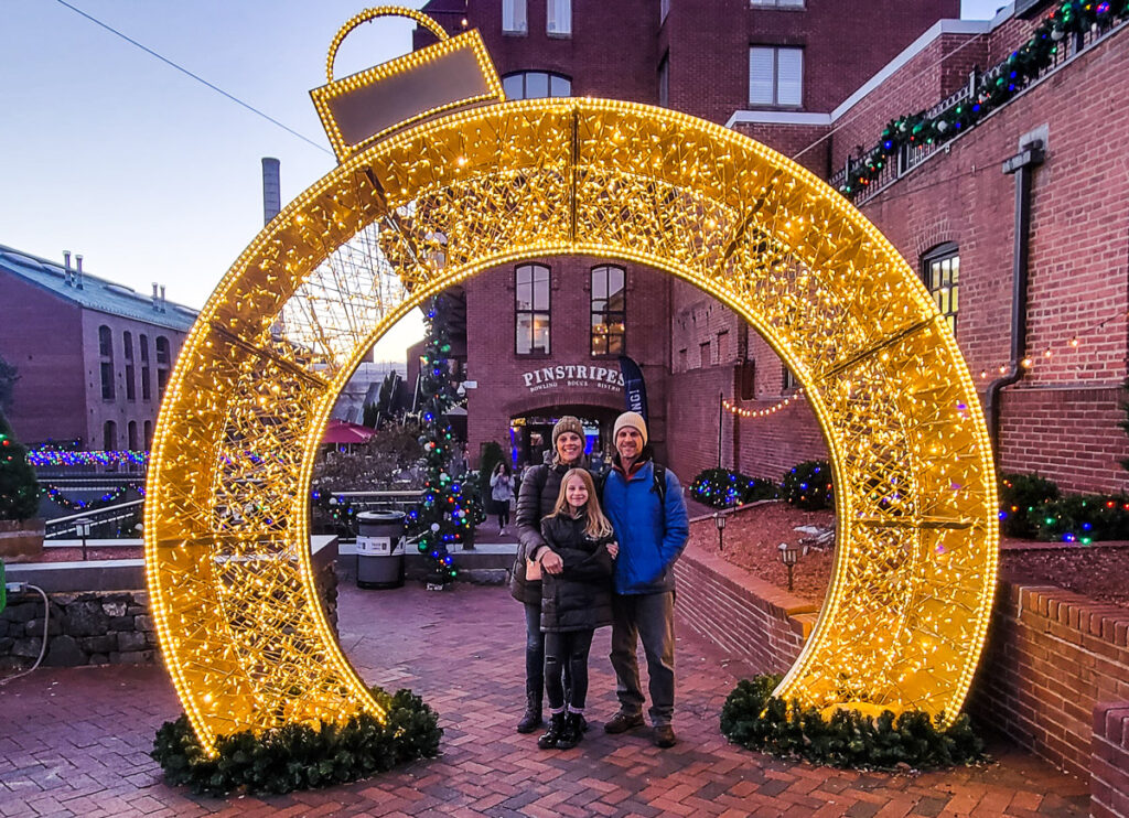 Parents and their daughters posing for a photo under an arch of Christmas lights