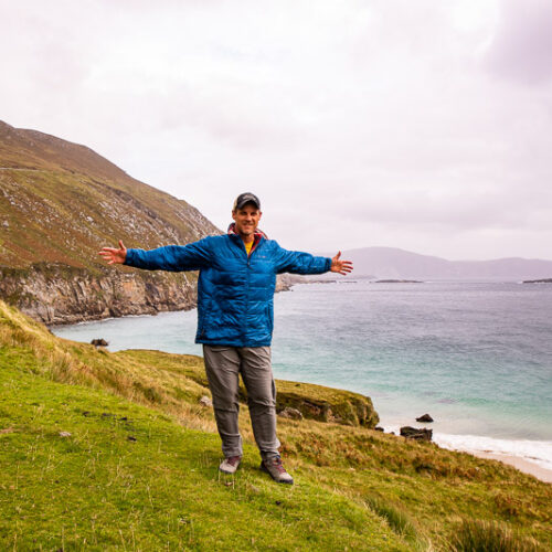 Man standing on a cliff overlooking a beach in Ireland