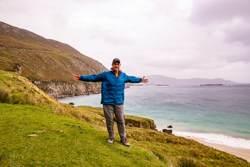 Man standing on a cliff overlooking a beach in Ireland