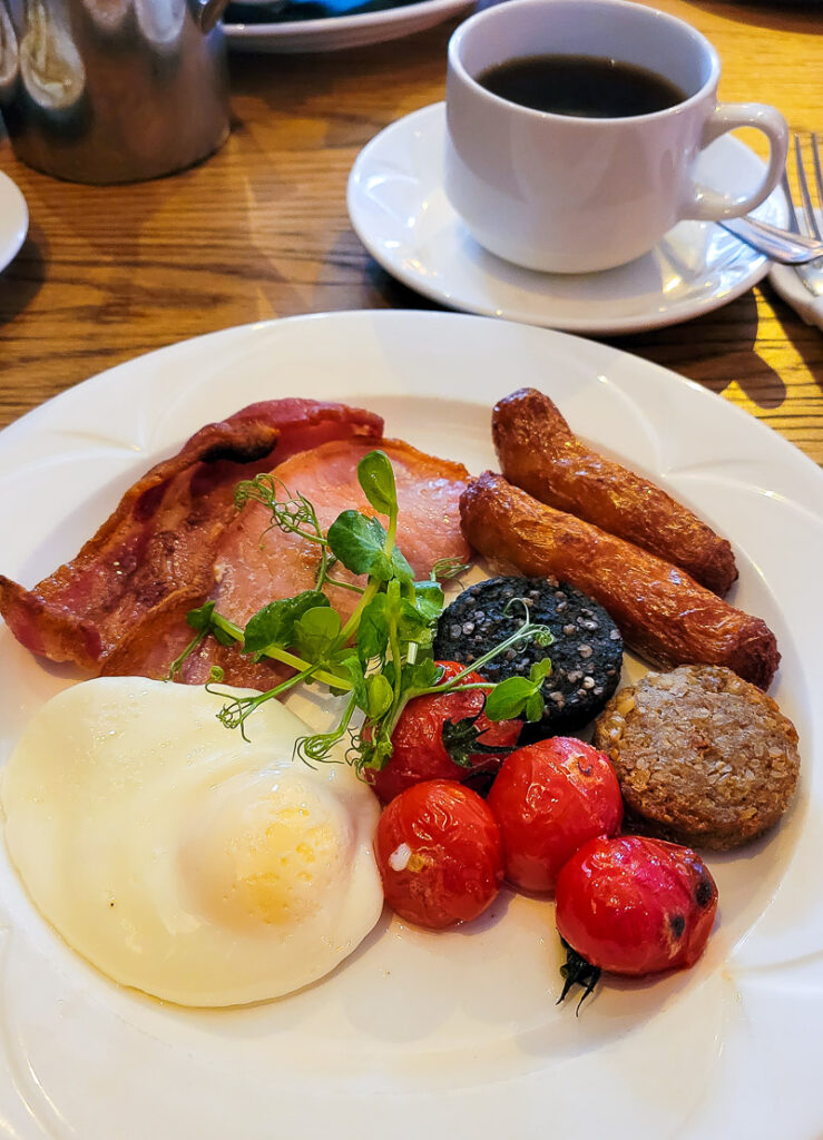 Eggs, sausages, bacon, pudding and tomatoes on a plate