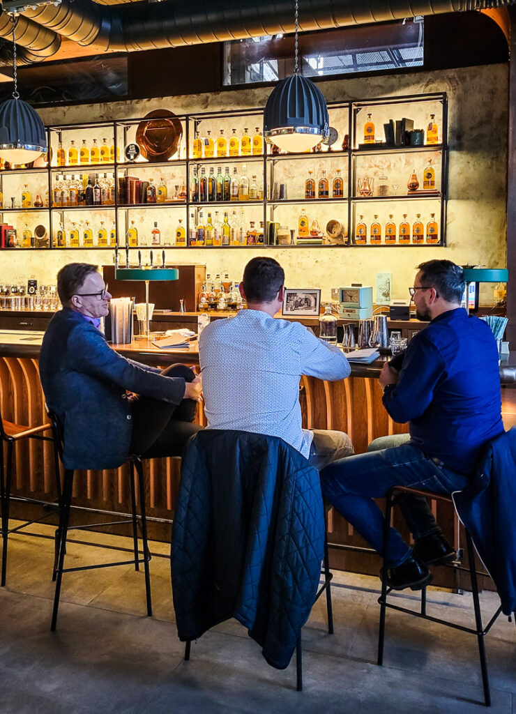 Three men sitting at a bar drinking Whiskey