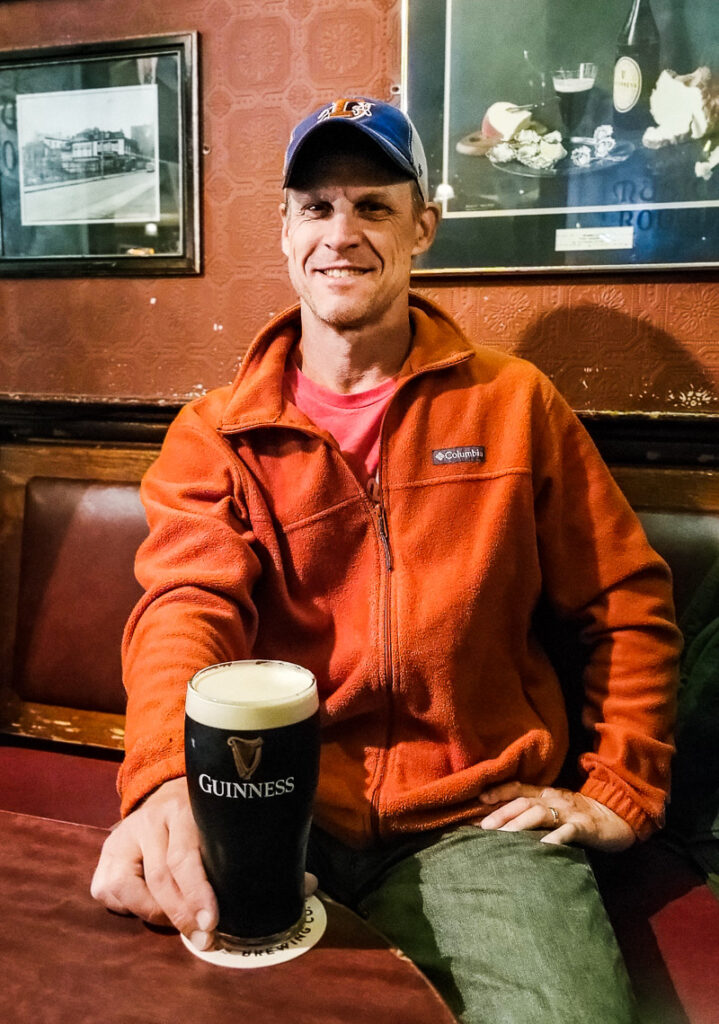 A man sitting in a pub with a pint of Guinness in front of him
