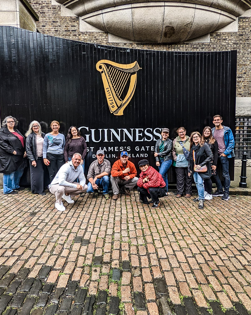 Group of people getting photo taken in front of a gate with the words Guinness on it