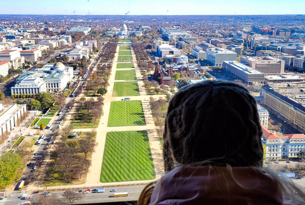 Girl looking out a window looking at the National Mall and US Capitol in DC