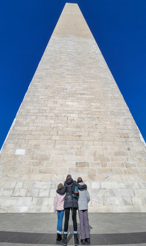 Mom and two daughters looking up at a 555 ft tall monument in DC