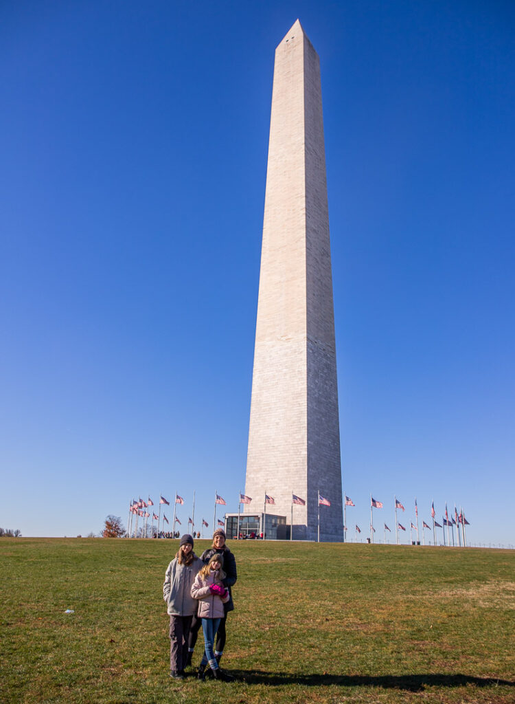 Mom and two daughters standing under the Washington Monument in DC