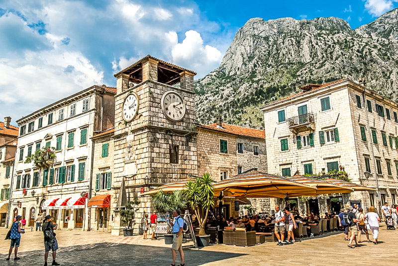 Clock tower on the square in the old town of Kotor. Montenegro with mountain peaks in the background