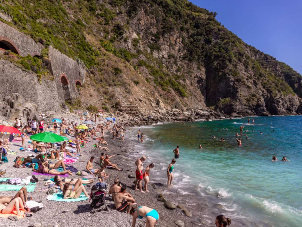 people sitting on rocky beach of  Riomaggiore 