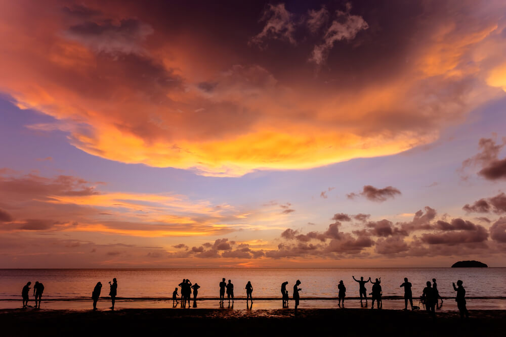 Silhouettes of people on the shore enjoying a beach sunset