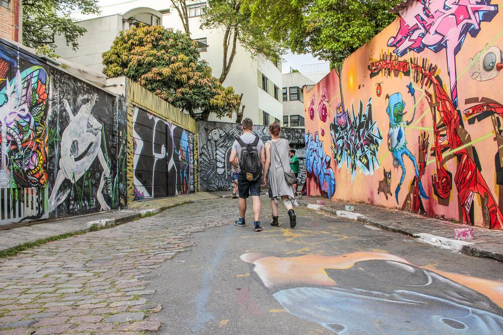 people walking down batman alley looking at street art