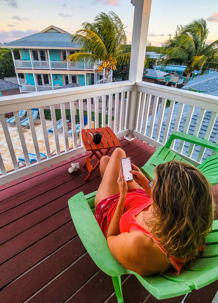 Lady on her phone sitting on a balcony overlooking palm trees