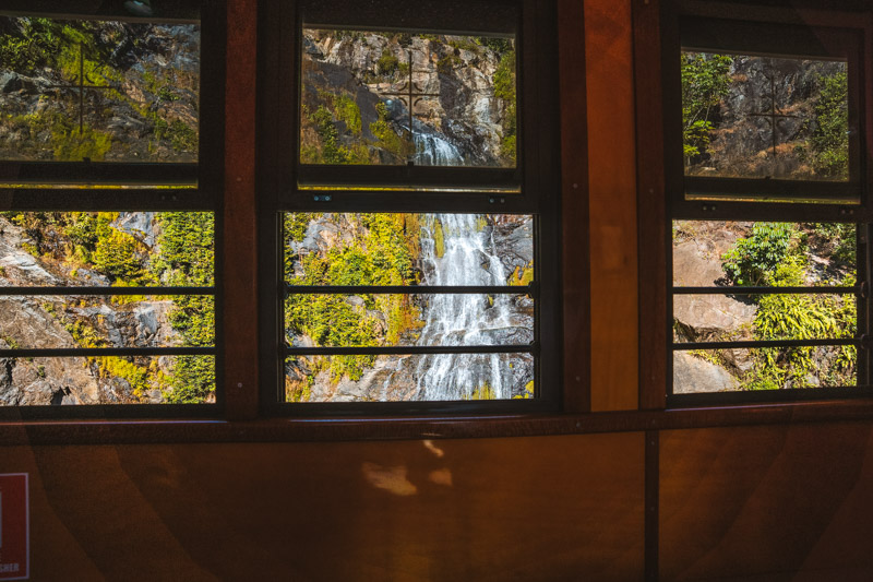 looking outside a train window at a waterfall