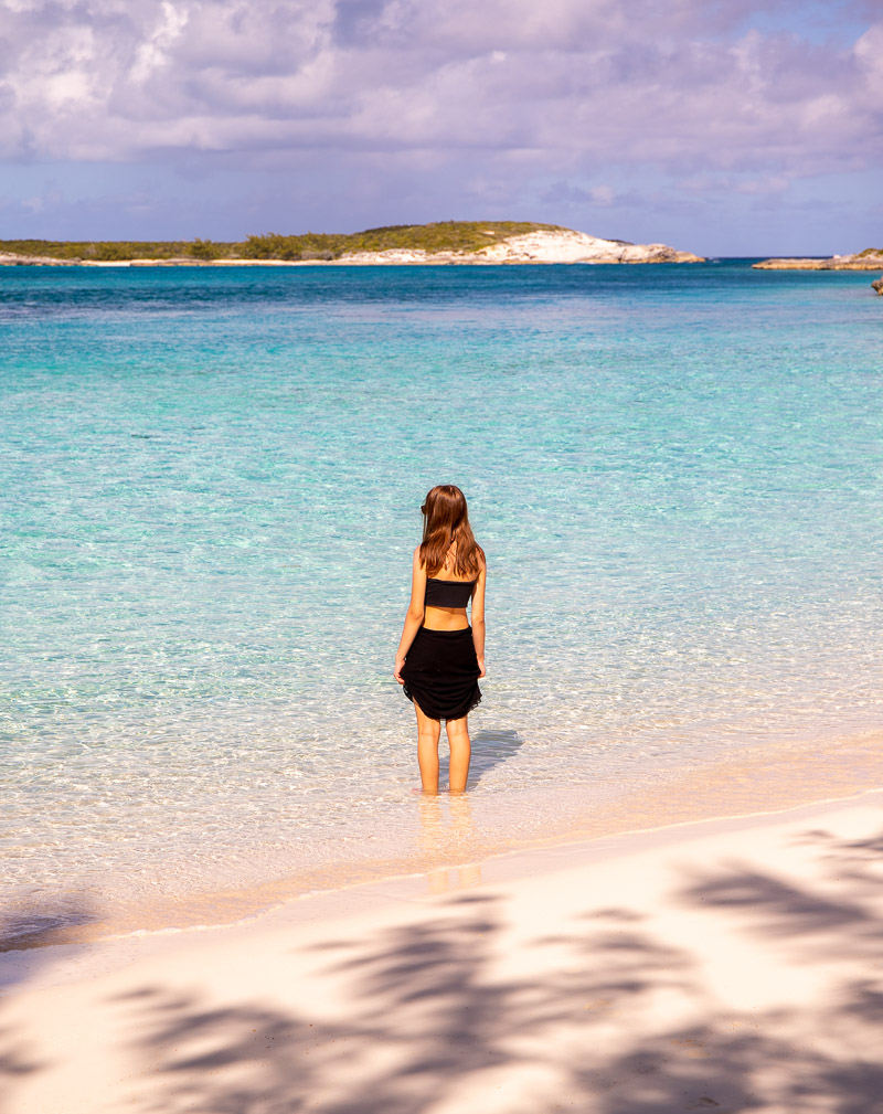 Girl standing in shallow water at the beach looking out over islands