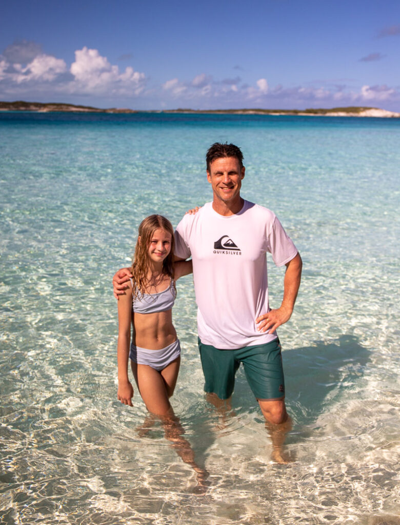 Father and daughter standing in shallow water at a beach