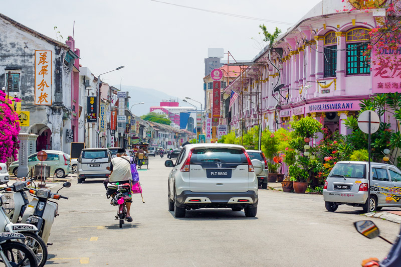 cars and bicycles on colorful street in george town