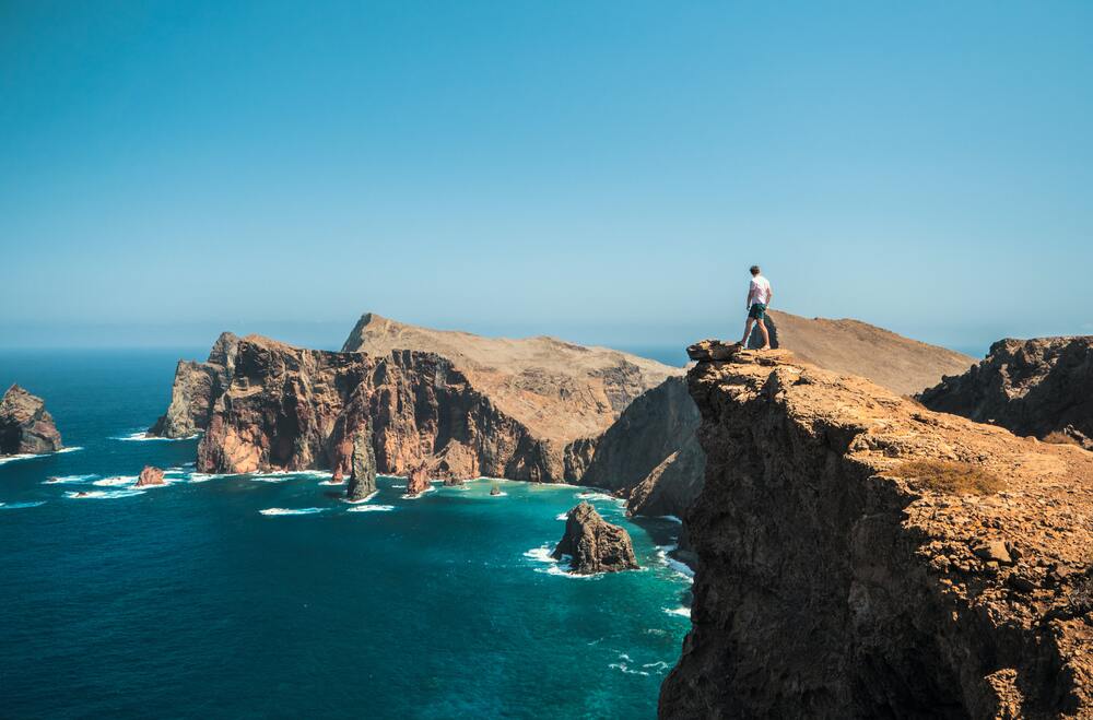person on cliffs overlooking rugged coastline