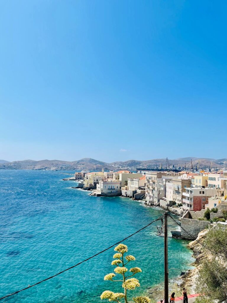 blue waters of syros with buildings on edge