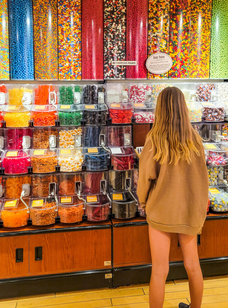 Girl standing in front of candy for sale in a store