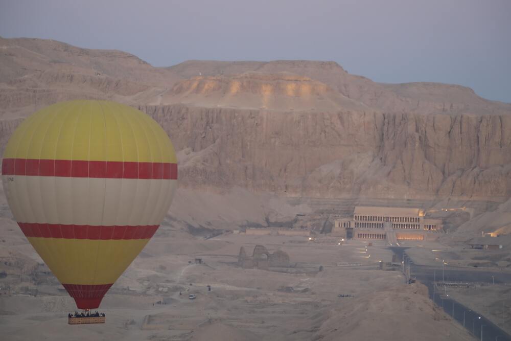 hot air balloon in front of desert cliffs
