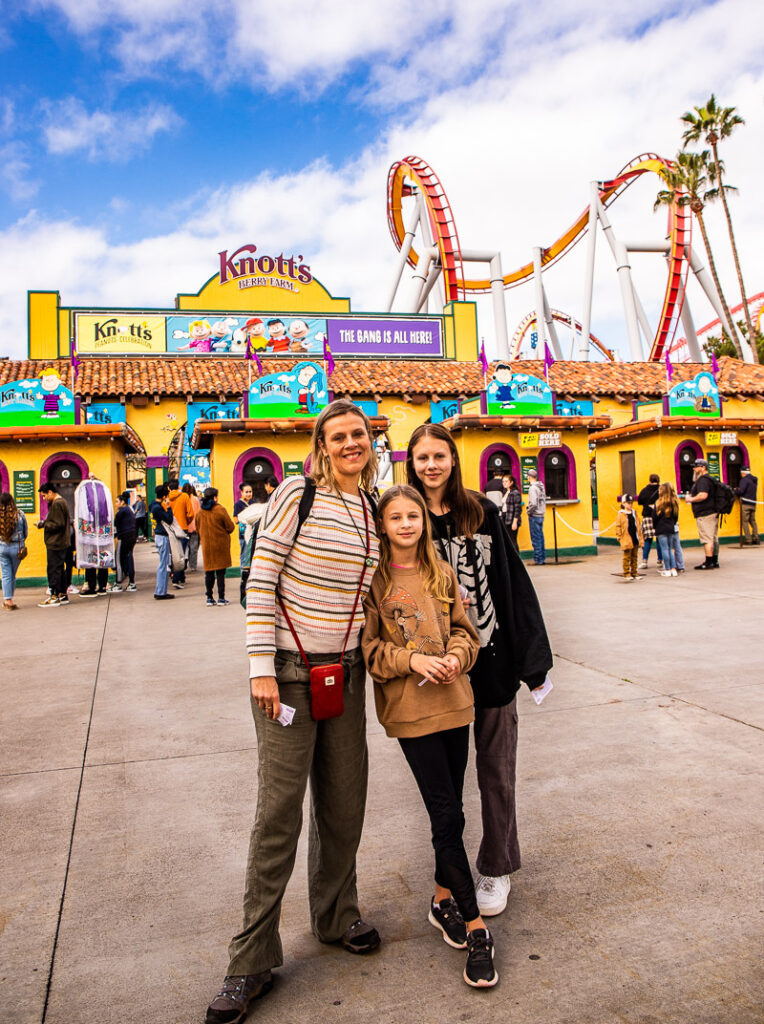 Mom and two daughters standing outside the entrance to a theme park called Knott's Berry Farm