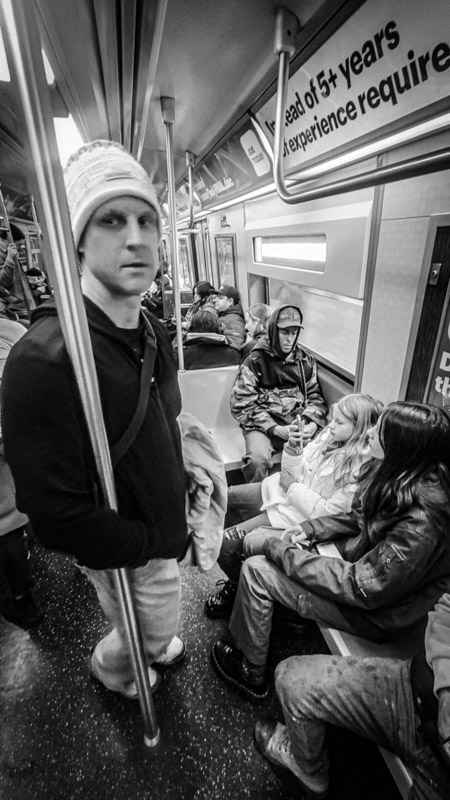 man leaning against pole on subway train
