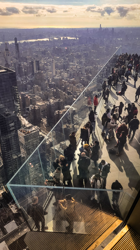 people standing on glass enclosed edge looking at nyc view