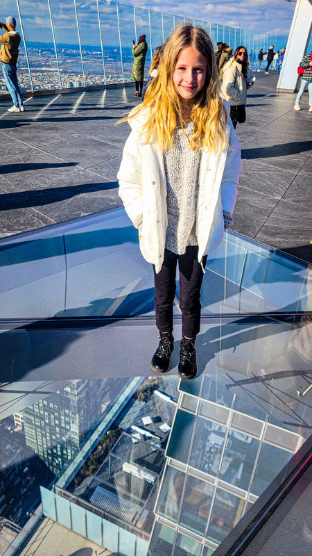 girl standing on glass floor at the edge nyc