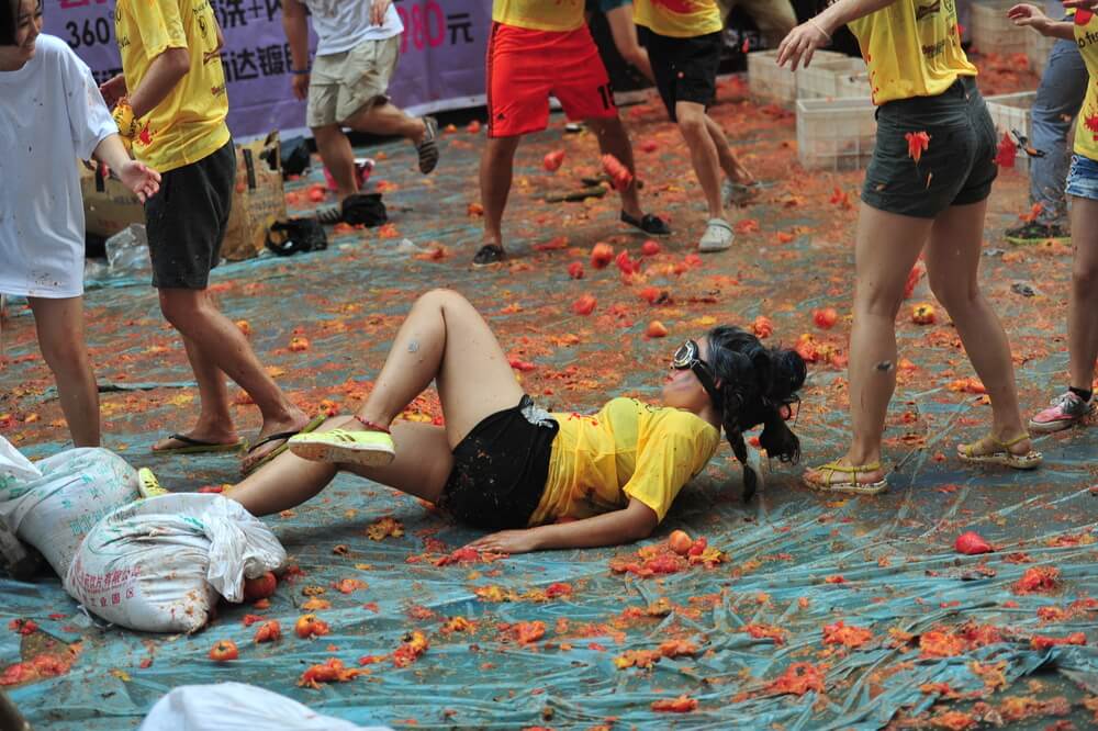 woman lyin gon ground covered in tomatoes La Tomatina