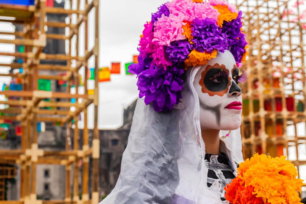 woman with painted face and flowers on head day of the dead mexico