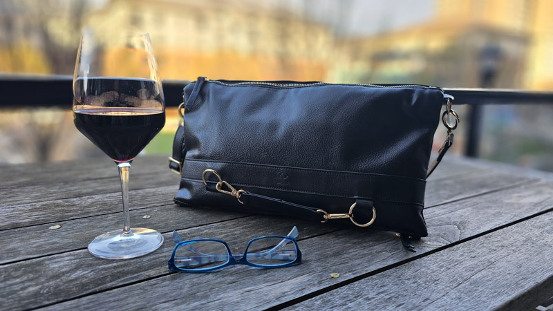 driibe travel purse on table with glass of red wine