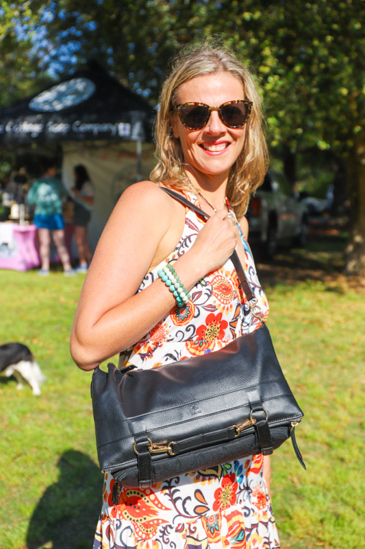 woman holding driibe black handbag and smiling