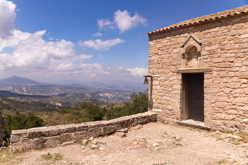 brick building of Agios Dimitrios Church with bell and views of the gulf