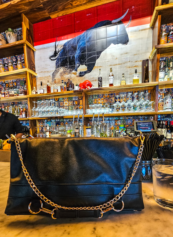 driibe handbag with gold chain sitting on bar